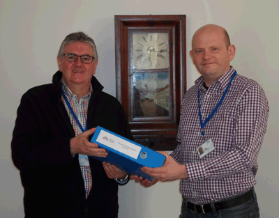 Photograph of John Simmons, acting NRS Records Manager, (right) handing over the NRS records management plan to Dr Hugh Hagan, Head of the Public Records (Scotland) Act Implementation Team.