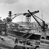 Photograph of the view of the Royal Navy Renown-Class battlecruiser HMS Repulse in the fitting out basin at John Brown & Co. shipyard, Clydebank looking aft from the starboard side of the bow showing the forward turrets and conning tower, 14 April 1916 (Crown Copyright, National Records of Scotland, UCS1/116/20/pg22)